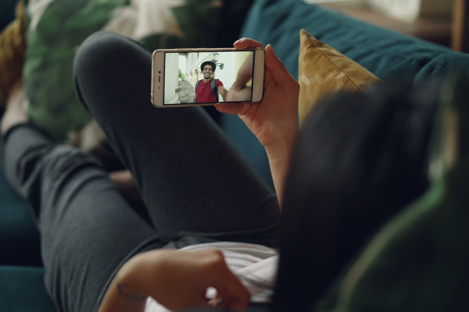 Une personne en appel vidéo sur son téléphone, dans son canapé