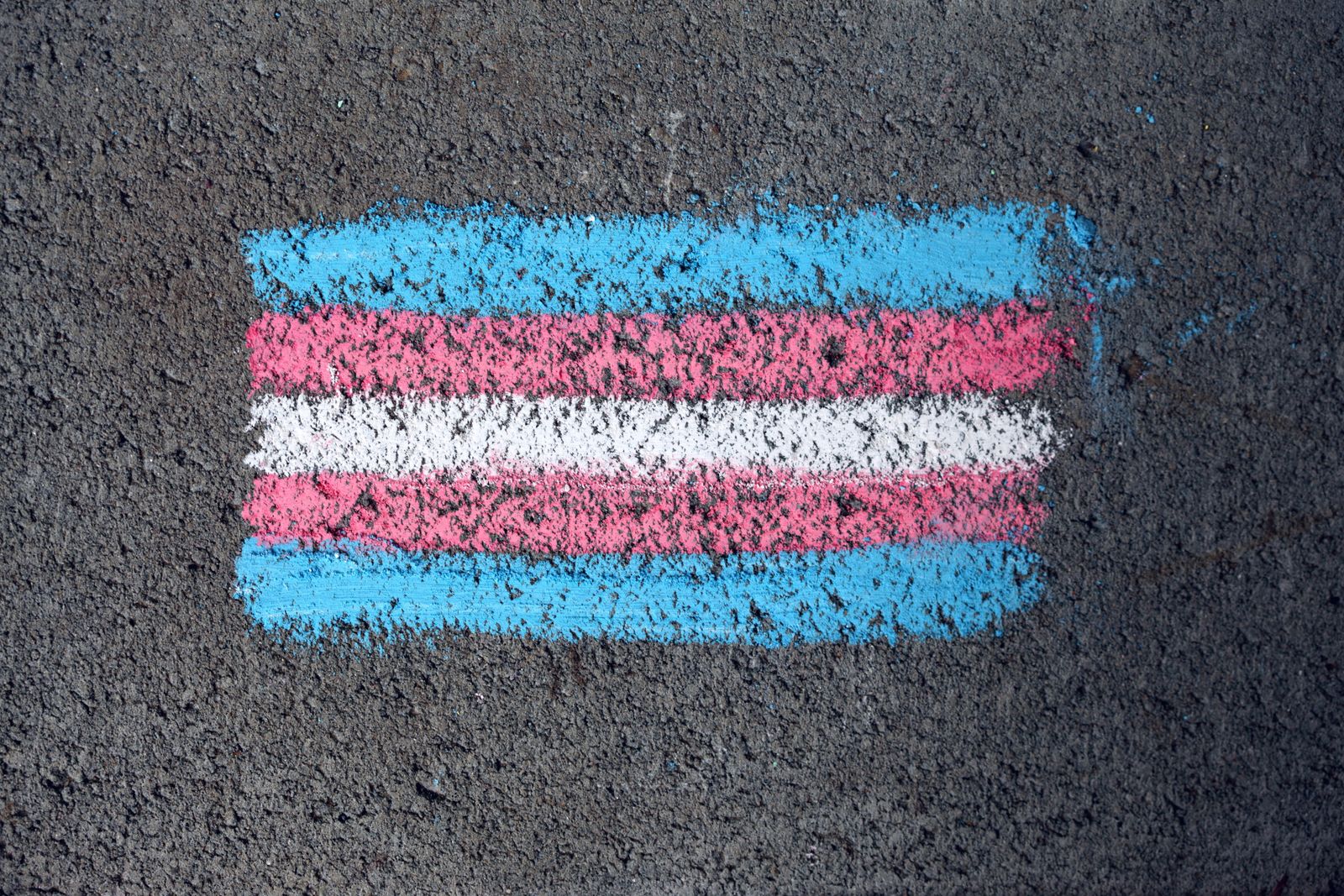 Le drapeau trans bleu, rose et blanc dessiné à la craie sur un trottoir